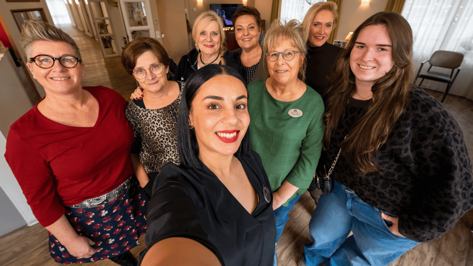 Selfie met acht lachende vrouwen van verschillende leeftijden die kijken naar de camera.