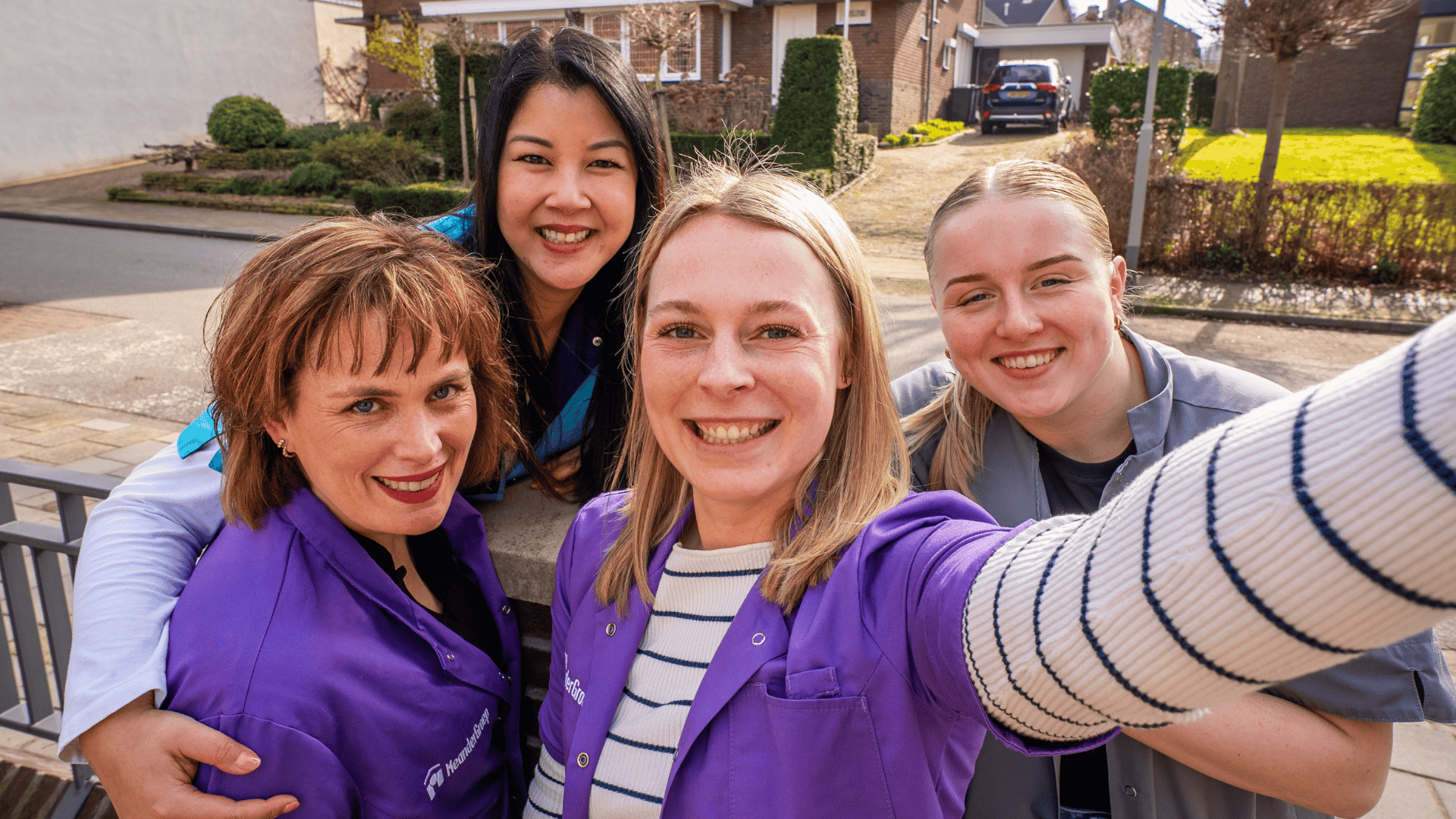 Vier lachende vrouwen maken een selfie in de bedrijfskleding van MeanderGroep.